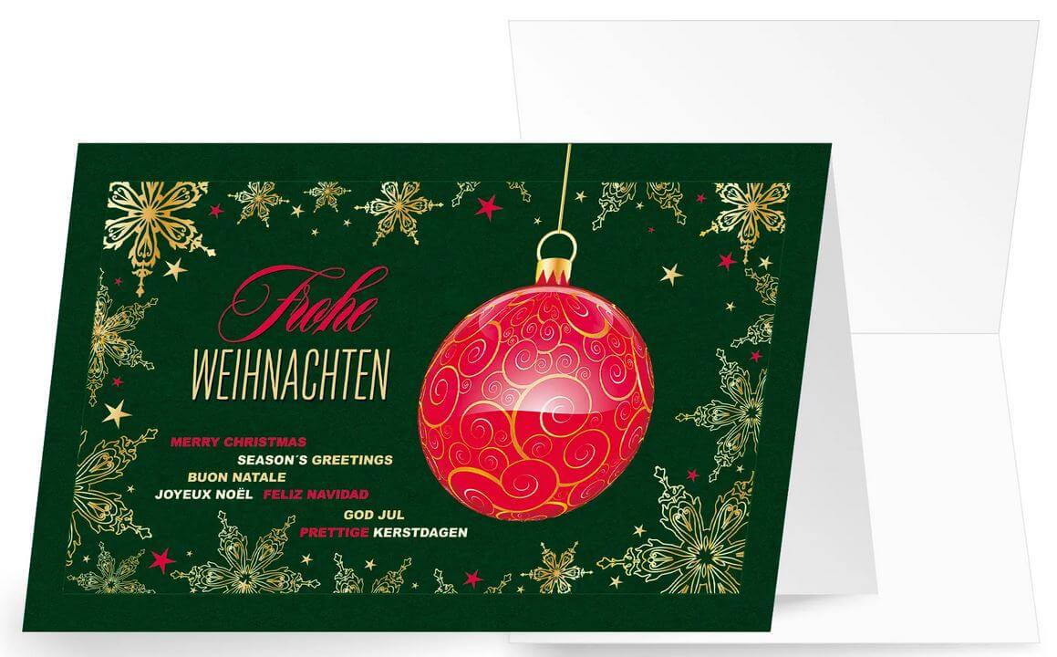 Festliche Weihnachtskarte in grün mit internationalen Grüßen und hängender Baumkugel