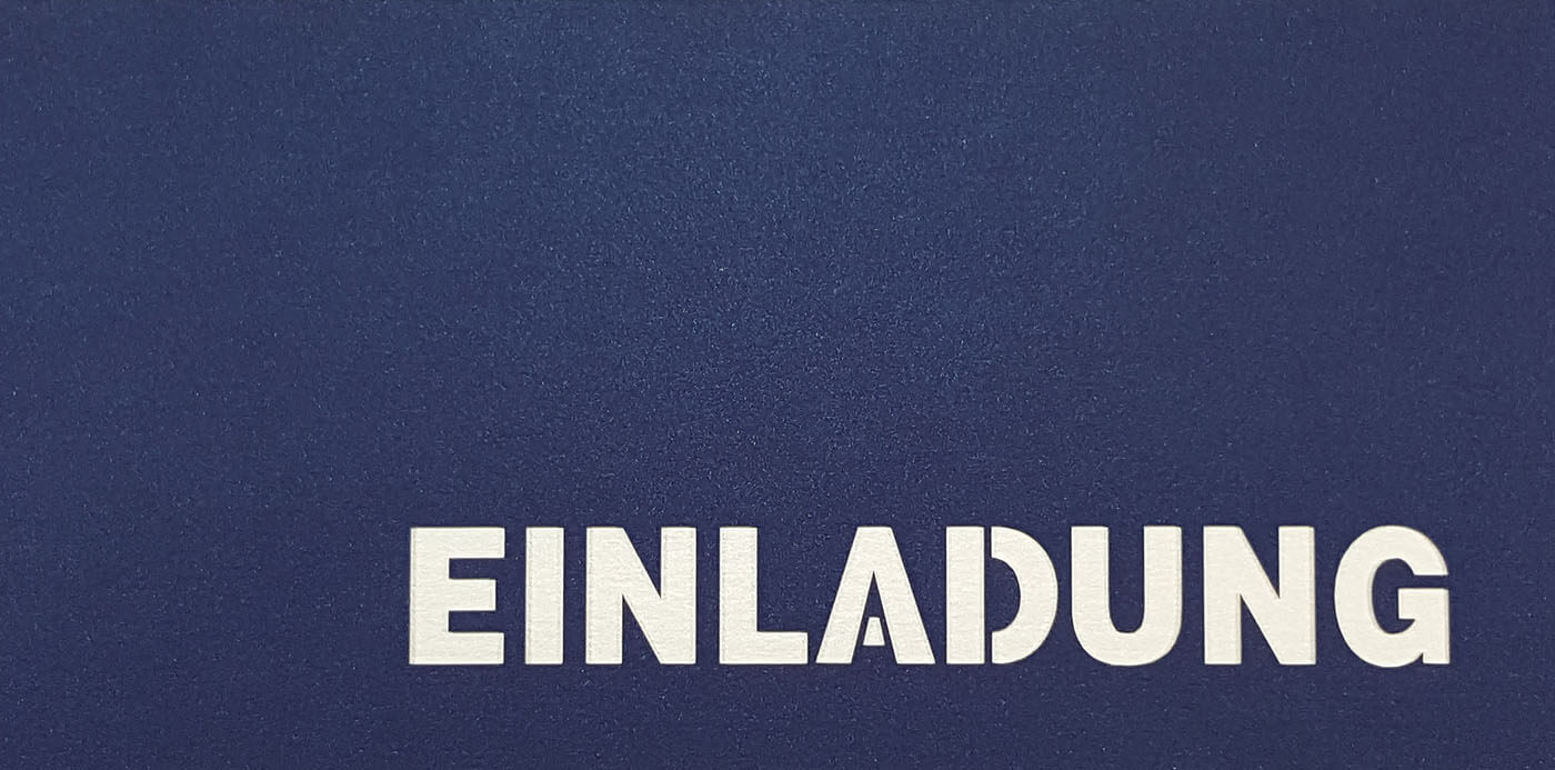 Dunkelblaue Einladungskarte DIN lang mit ausgestanztem Schriftzug "Einladung" und weißem Einlegeblatt