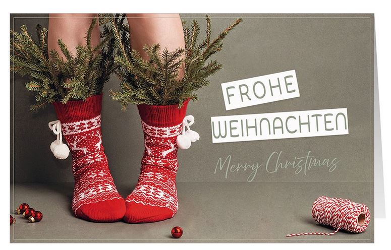 Fröhliche Weihnachtskarte mit deutsch-englischem Gruß, roten Stricksocken und eingesteckten Zweigen