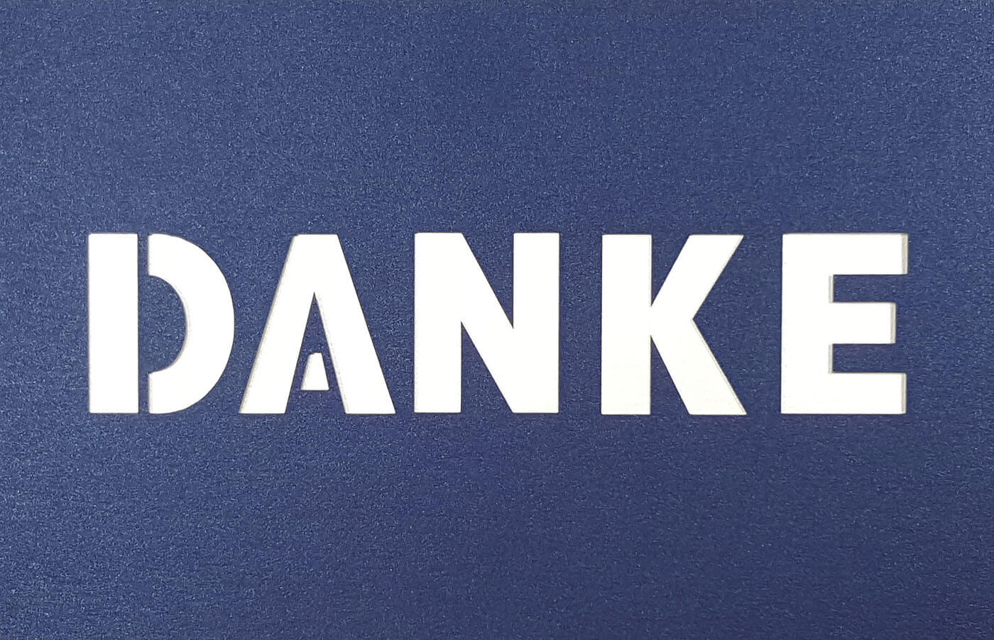 Dunkelblaue Danksagungskarte querdoppelt mit zentral ausgestanztem Schriftzug "DANKE" und weißem Einlegeblatt