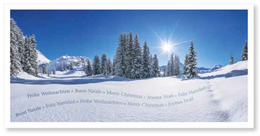 Winterliche Weihnachtskarte im Panorama-Querformat, verschneite Berglandschaft mit Wald und Sonnenaufgang im wolkenlosen, strahlend blauem Himmel