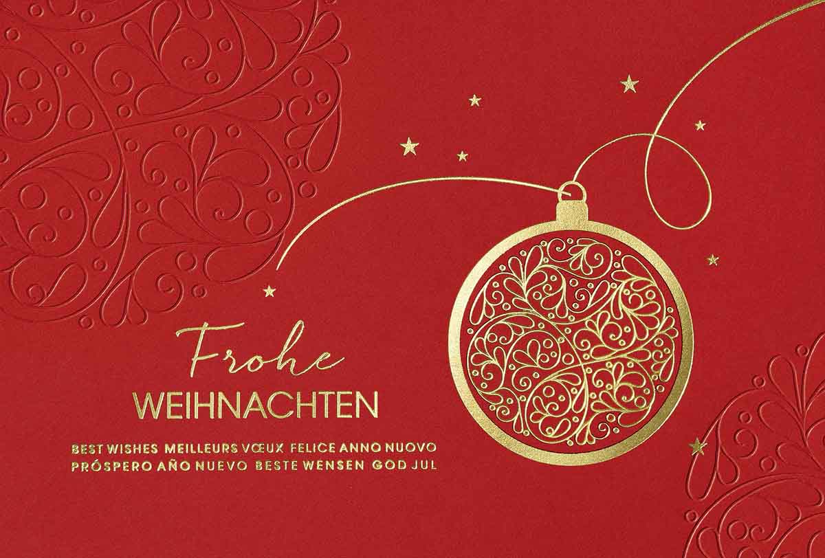 Rote Weihnachtskarte mit ornamentverzierter Christbaumkugel und internationalen Grüßen