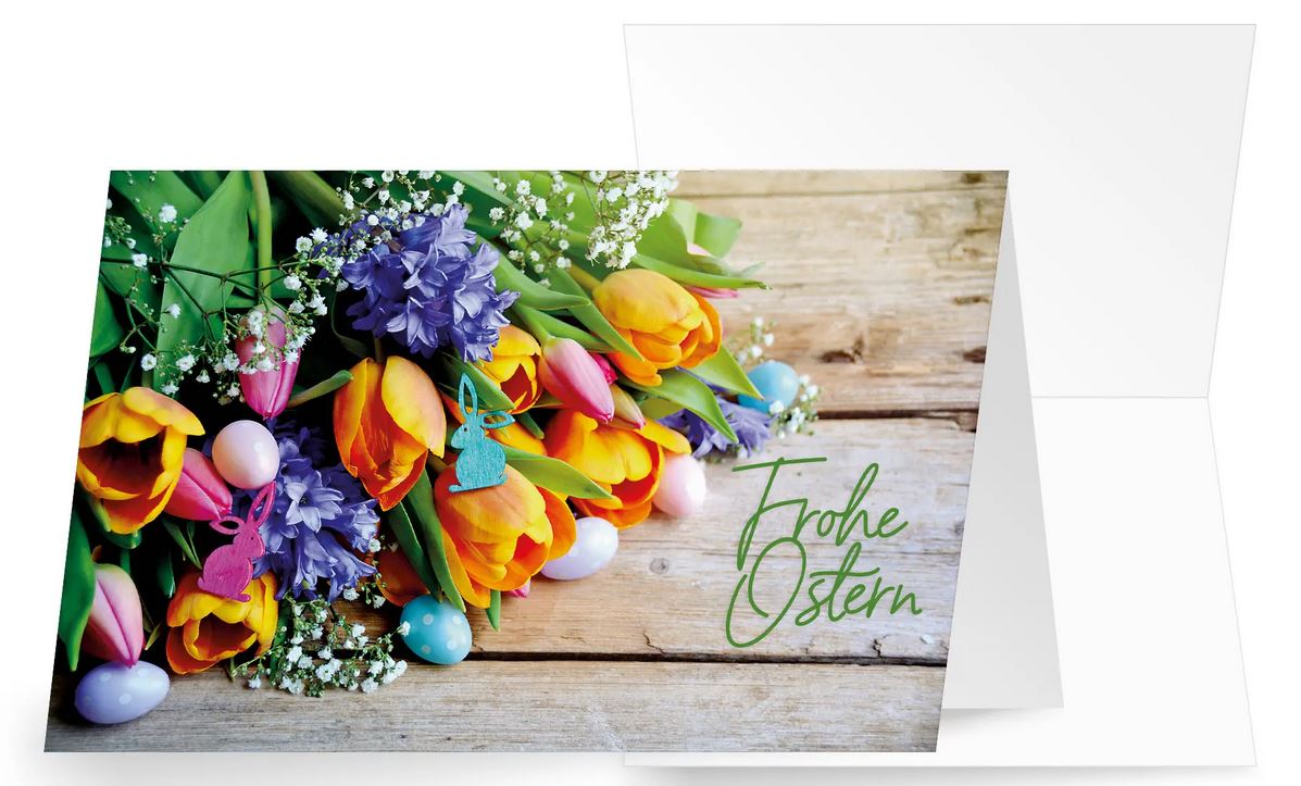 Bunte Ostergrüße mit Frühlingsblumen, kleinen Eiern und "Frohe Ostern" auf Holzbohlen