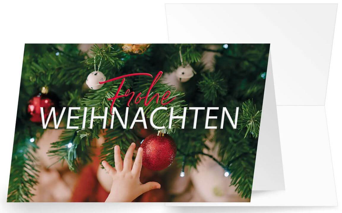 Traditionelle Weihnahctskarte mit roten und weißen Kugeln am Baum und kleiner Kinderhand