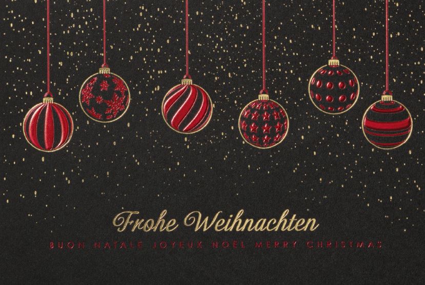 Dunkelgraue Weihnachtskarte mit hängenden Christbaumkugeln und "Frohe Weihnachten" in mehreren Sprachen