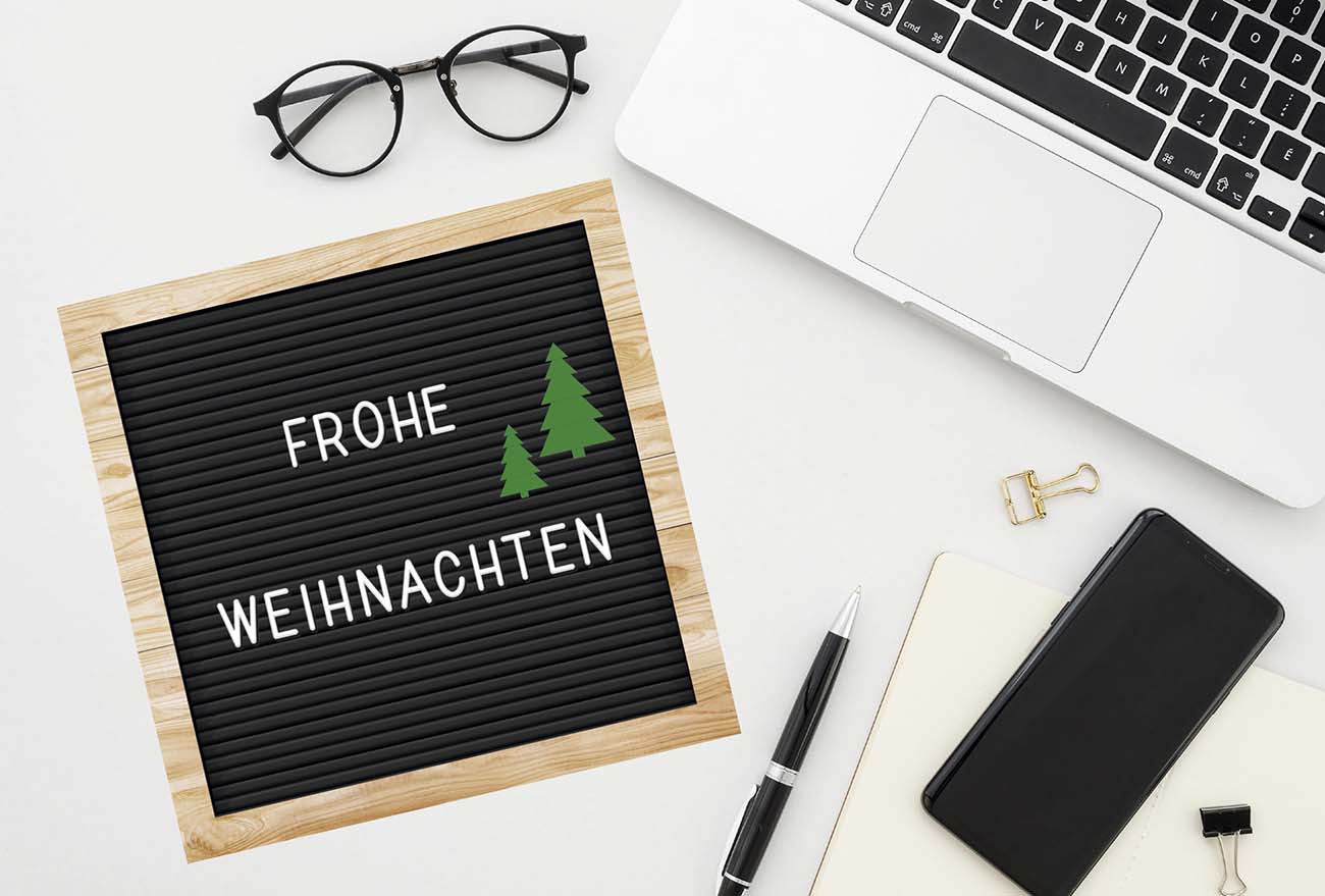 Geschäftliche Weihnachtskarte mit Weihnachtsgruß und Büro-Utensilien wie Handy und Brille