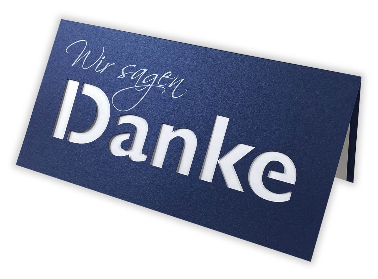 Blaue Dankkarte DIN lang mit gedrucktem "Wir sagen", ausgestanztem Schriftzug "Danke" und passenden Einlegeblatt