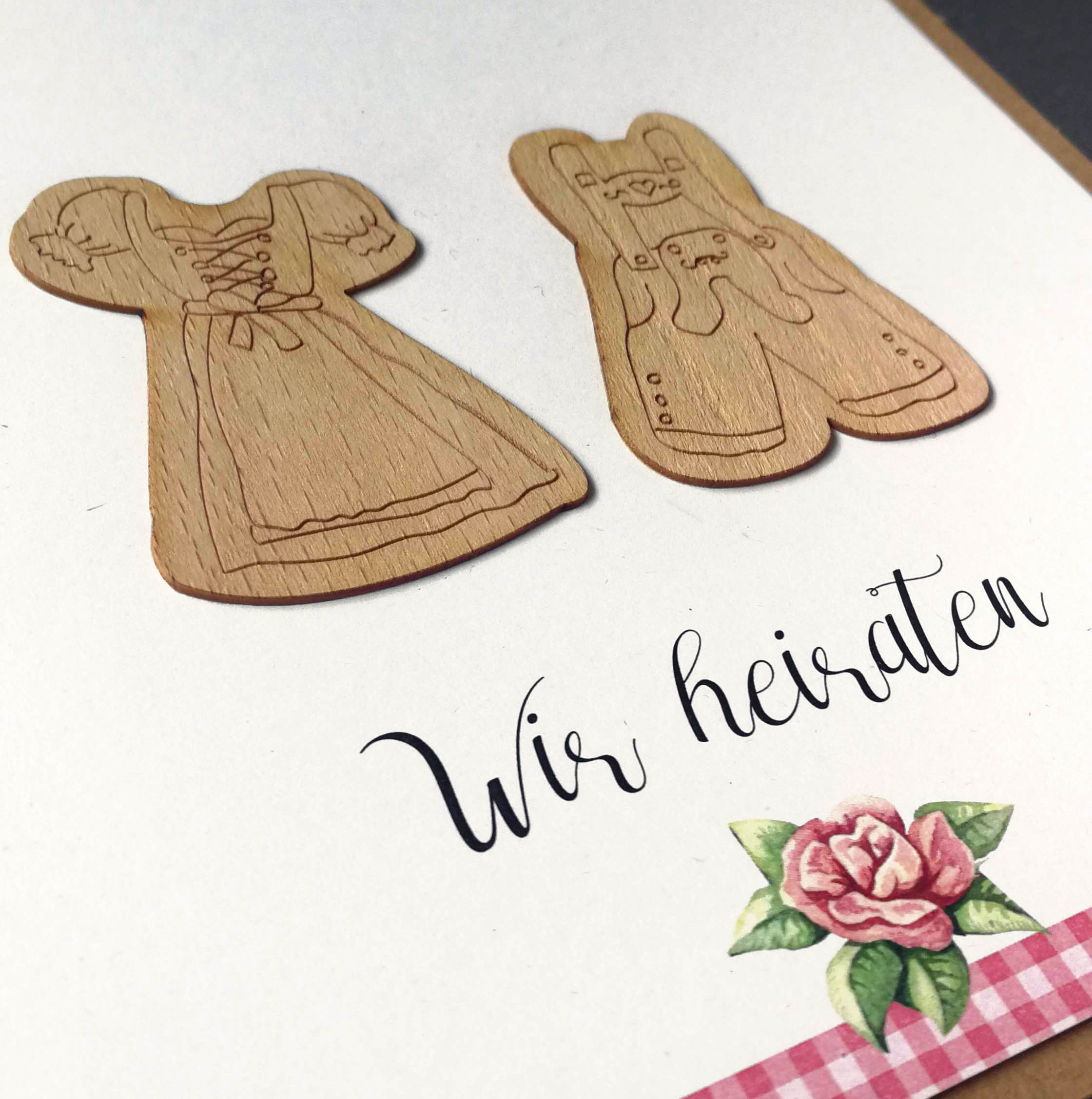 Detailansicht der Holzapplikation von Dirndl und Lederhose auf traditioneller Hochzeitskarte 