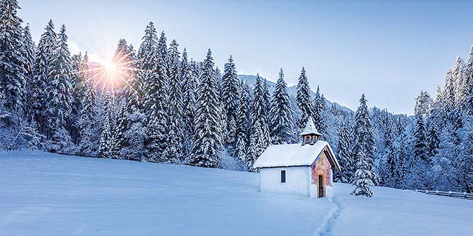 Winterlandschaft Weihnachtskarte im DIN lang Format mit verschneiter Bergkapelle und Winterwald