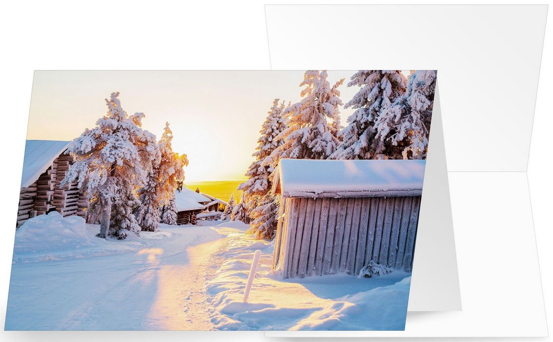 Winter-Weihnachtskarte mit Weg zwischen Holzhütten im Licht der Sonne